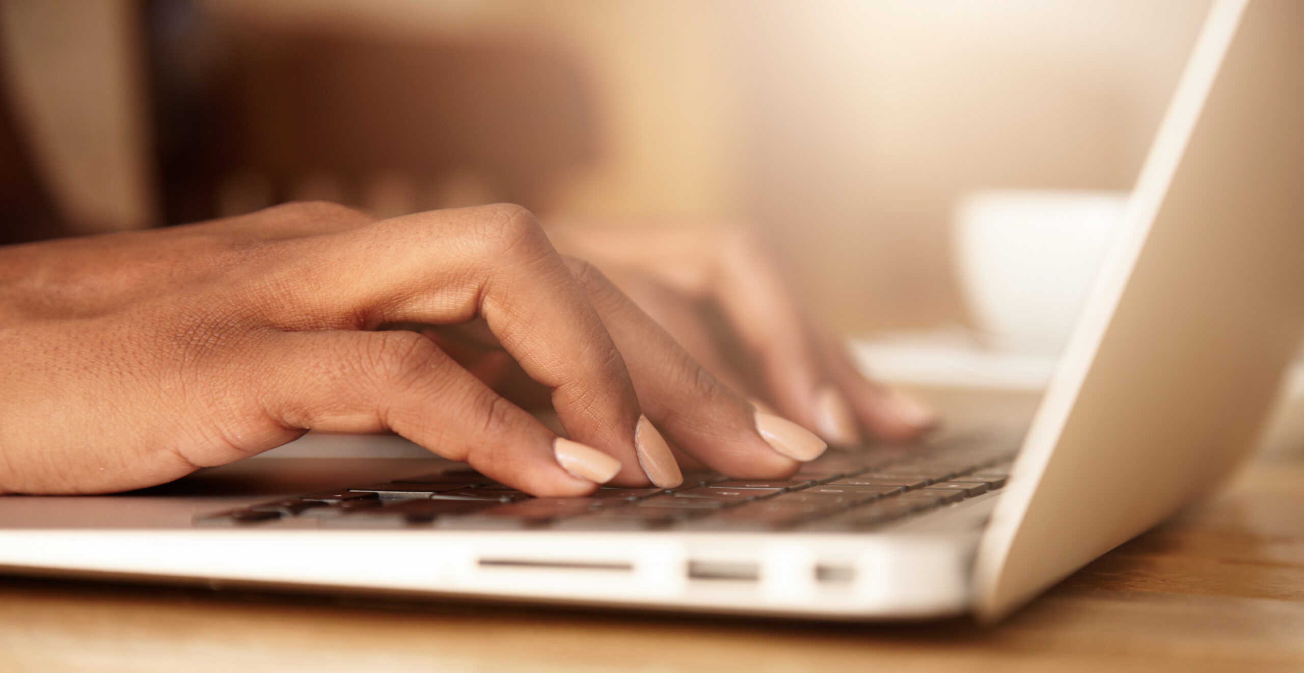 Woman's hands typing on a laptop